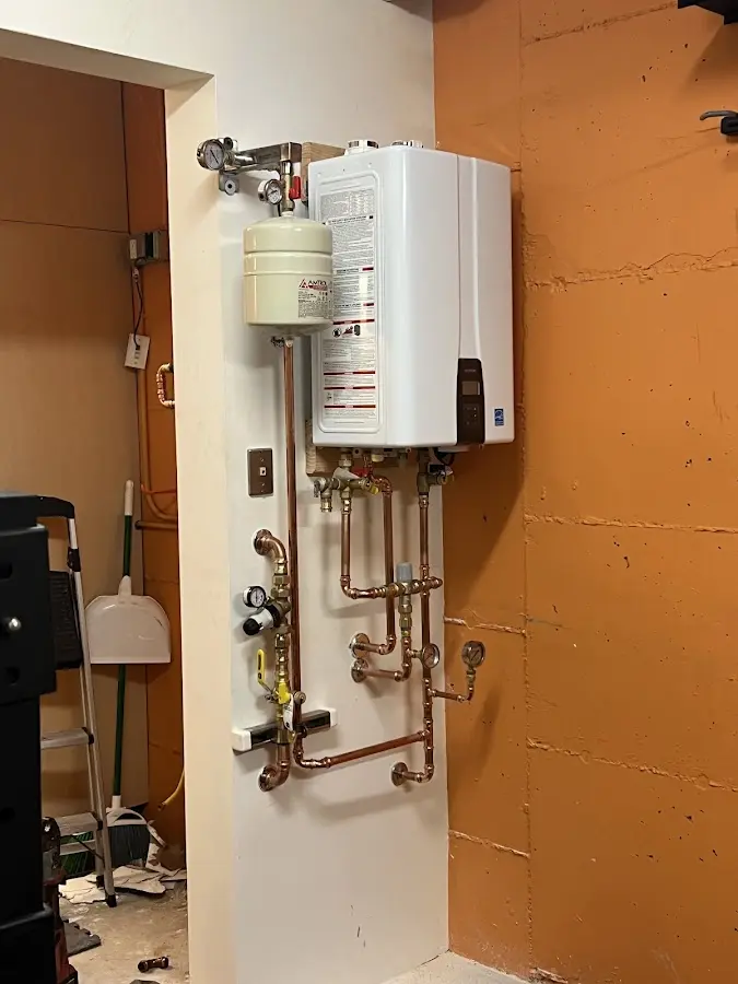Plumbing technician inspecting water heater connections in Upper Freehold